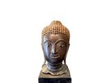 statue représentant une tête de Bouddha posée sur un socle, sur fond blanc