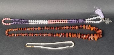 trois rangées de perles et un collier sur un fond noir