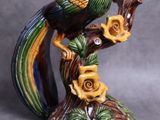 une figurine représentant un oiseau perché sur une branche d'arbre