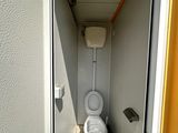 a white toilet in a small room with a yellow door