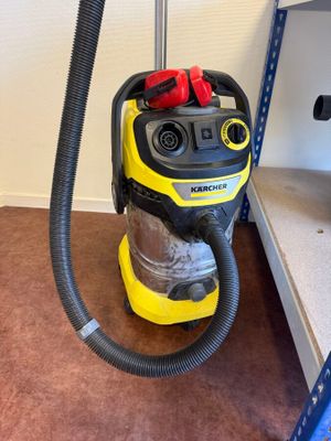 yellow and black vacuum cleaner sitting on the floor next to a shelf