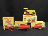 three toy trucks and a tractor are sitting next to each other