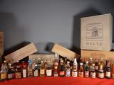 Plusieurs bouteilles d'alcool sont alignées sur une table rouge