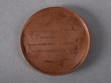 an old bronze medal with a poem on it sitting on a table