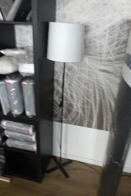 une étagère noire sur laquelle est posée une lampe, dans un coin de la pièce