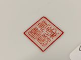 an image of a close up of a white plate with a red design on it
