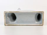 a white vase with two holes in it on a table