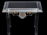 une table en plexiglas transparent avec un plateau noir et doré