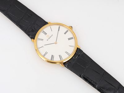 gros plan d'une montre sur une surface blanche avec un bracelet noir