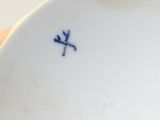 someone is holding a white plate with a blue cross on it