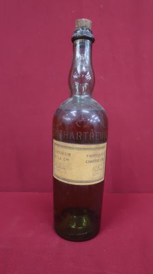 an old bottle of whiskey sitting on a red surface