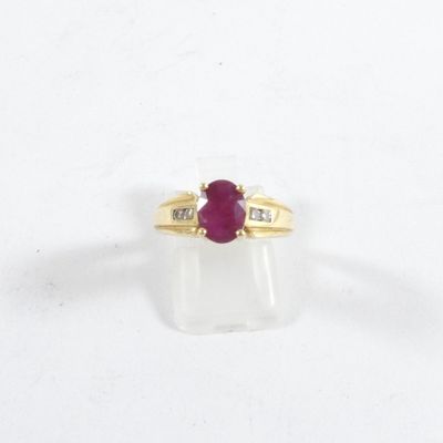 gros plan d'une bague en or avec un rubis et des diamants