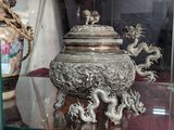 un vase en argent orné d'un dragon, exposé dans une vitrine