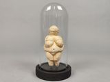 une photo représentant une figurine de femme assise sous un dôme en verre