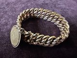 a close up of a bracelet with a coin on a purple surface