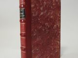 a red book with gold trim sitting on top of a white surface