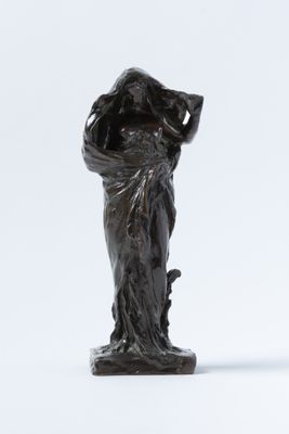 une vieille statue en bronze représentant une femme avec un panier sur la tête