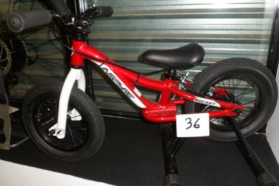 un vélo rouge et blanc garé devant la porte d'un garage
