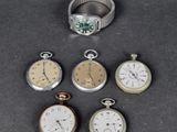plusieurs modèles différents de montres de poche et une bague posés sur une table