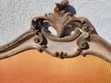 an orange couch with a gold frame and a white wall