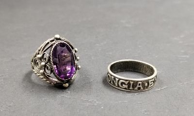 two silver rings with a purple stone sitting on top of a table