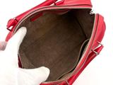 a person holding a red purse with a white cat inside of it