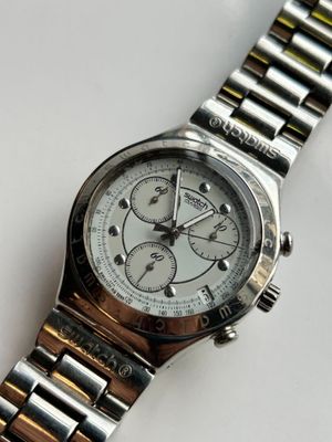 une montre argentée et dorée posée sur une surface blanche