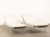 pair of lounge chairs in white leather with chrome legs and foot rest
