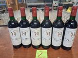 six bouteilles de vin rouge sont alignées sur une table