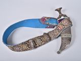 une ceinture bleue ornée d'un couteau, posée sur un fond blanc