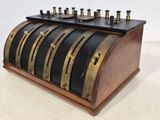 an old fashioned cash register with five rows of coins on top of it