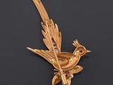 an image of a gold bird broochle on a black background