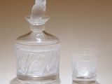 un bocal en verre orné d'un oiseau, à côté d'un verre