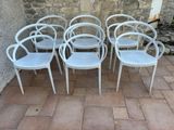 six white chairs sitting in front of a stone wall