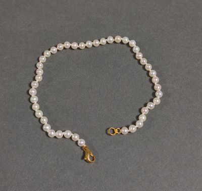 a close up of a white pearl bracelet with a gold clasp