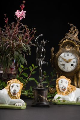 deux figurines de lions assis à côté d'une horloge