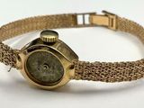 une image représentant une montre-bracelet en or avec un cadran vert