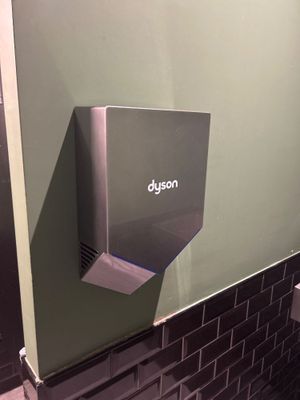 une photo d'une cabine de toilettes avec un sèche-mains fixé au mur