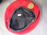 a red beret with a coin on top of it