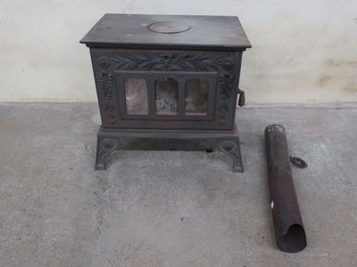 a small stove sitting next to a pipe on the floor