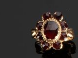 un gros plan d'une bague en or sertie d'une pierre rouge au centre