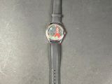 the watch is sitting on a black surface with a red flower on it