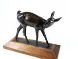 statue of a deer on a wooden base on a white background