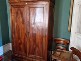 une armoire en bois placée dans un coin de la pièce, à côté d'un fauteuil