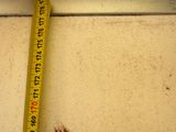 measuring tape on the edge of a window sill to measure the height of a window