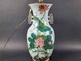 a white vase with pink flowers and green leaves on it