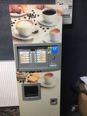a coffee vending machine with a cup of coffee on top of it
