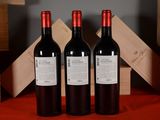 three bottles of red wine sitting next to each other on a table