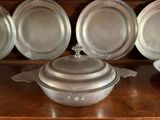 many silver dishes on a wooden shelf next to each other