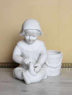 a white statue of a child sitting on the floor